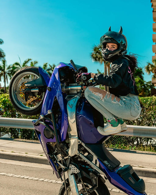 Stunt rider Robyn doing wheelie on her violet Kawasaki motorcycle