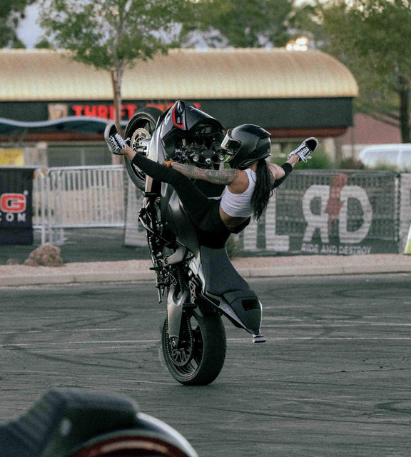 Ashley Dammela doing a wheelie on her black motorcycle 